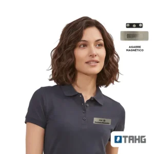 Mujer con polera piqué gris oscuro y name tag de acero con un logo de muestra en el pecho; arriba, el agarre magnético